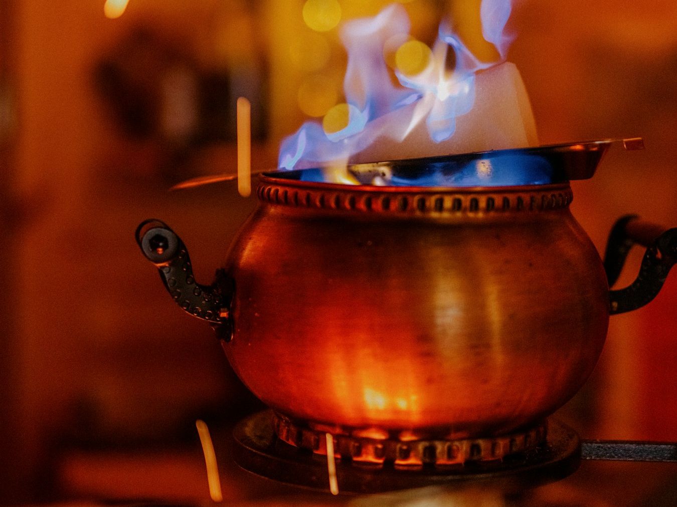 Brennender Zuckerhut über einem kupfernen Kessel mit Feuerzangenbowle