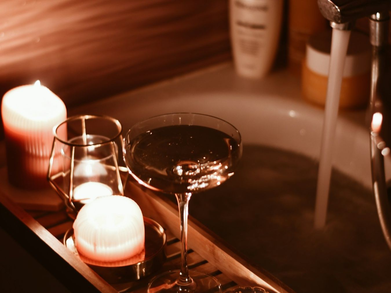 Kerzen und eine Sektschale auf dem Wannenbrett einer Badewanne
