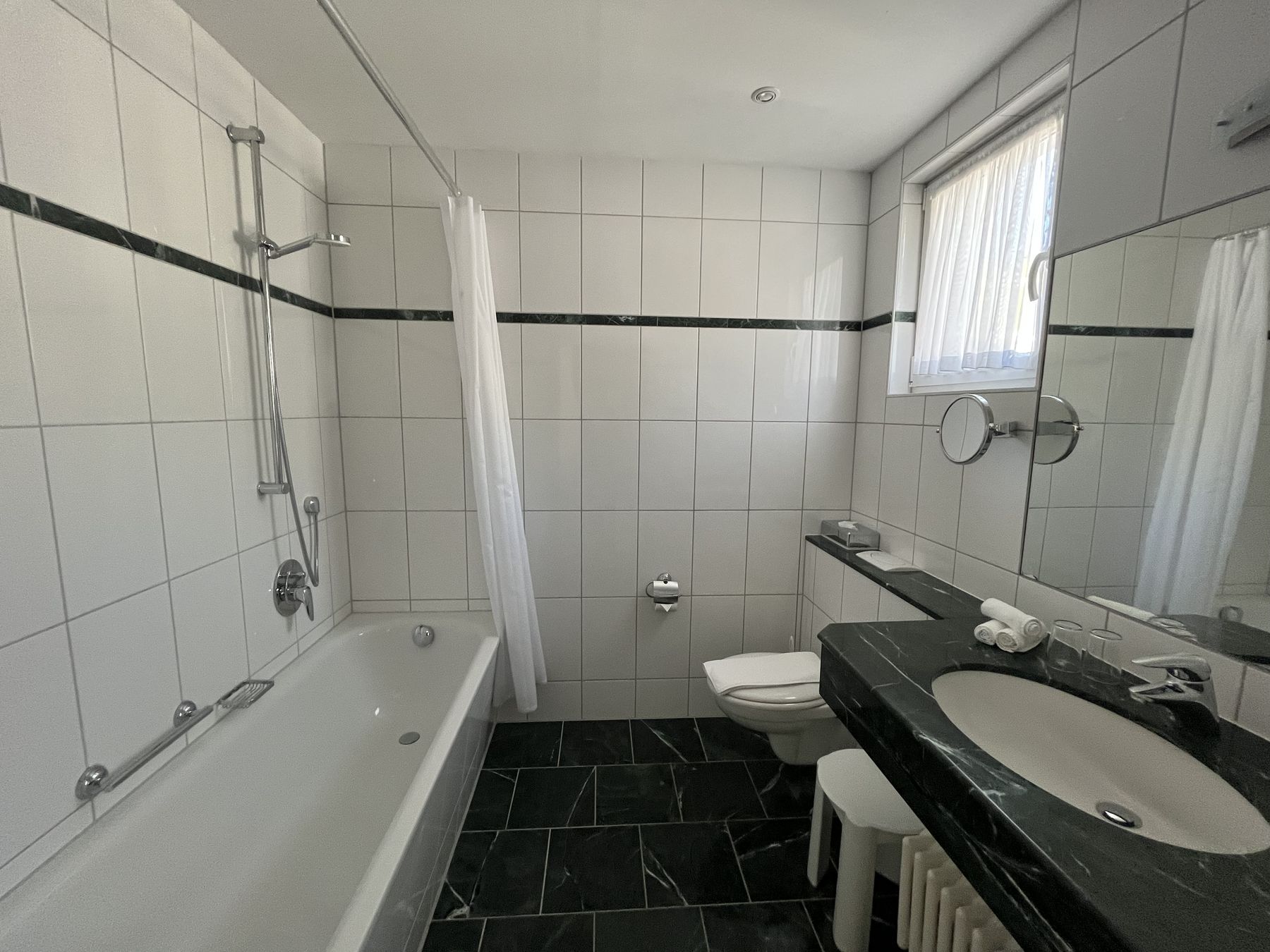 Bad mit Badewanne, Duschvorhang und dunklem Waschtisch