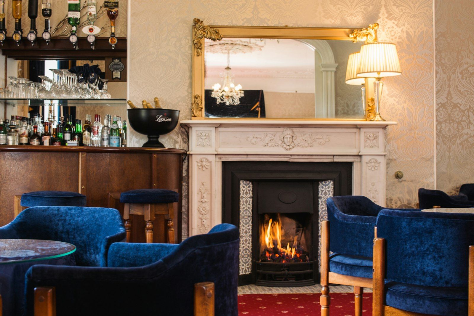 Gemütliche Lounge mit Kamin, Sesseln und einer kleinen Bar mit Flaschen und Gläsern