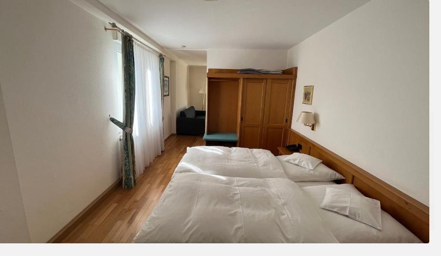 Schlafbereich mit Doppelbett, dahinter der Wohnbereich mit Sofa