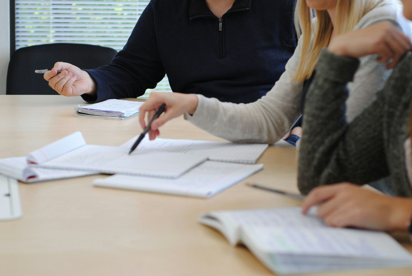 Workshop-Runde an einem Tisch mit Notizblöcken, Unterlagen und Stiften